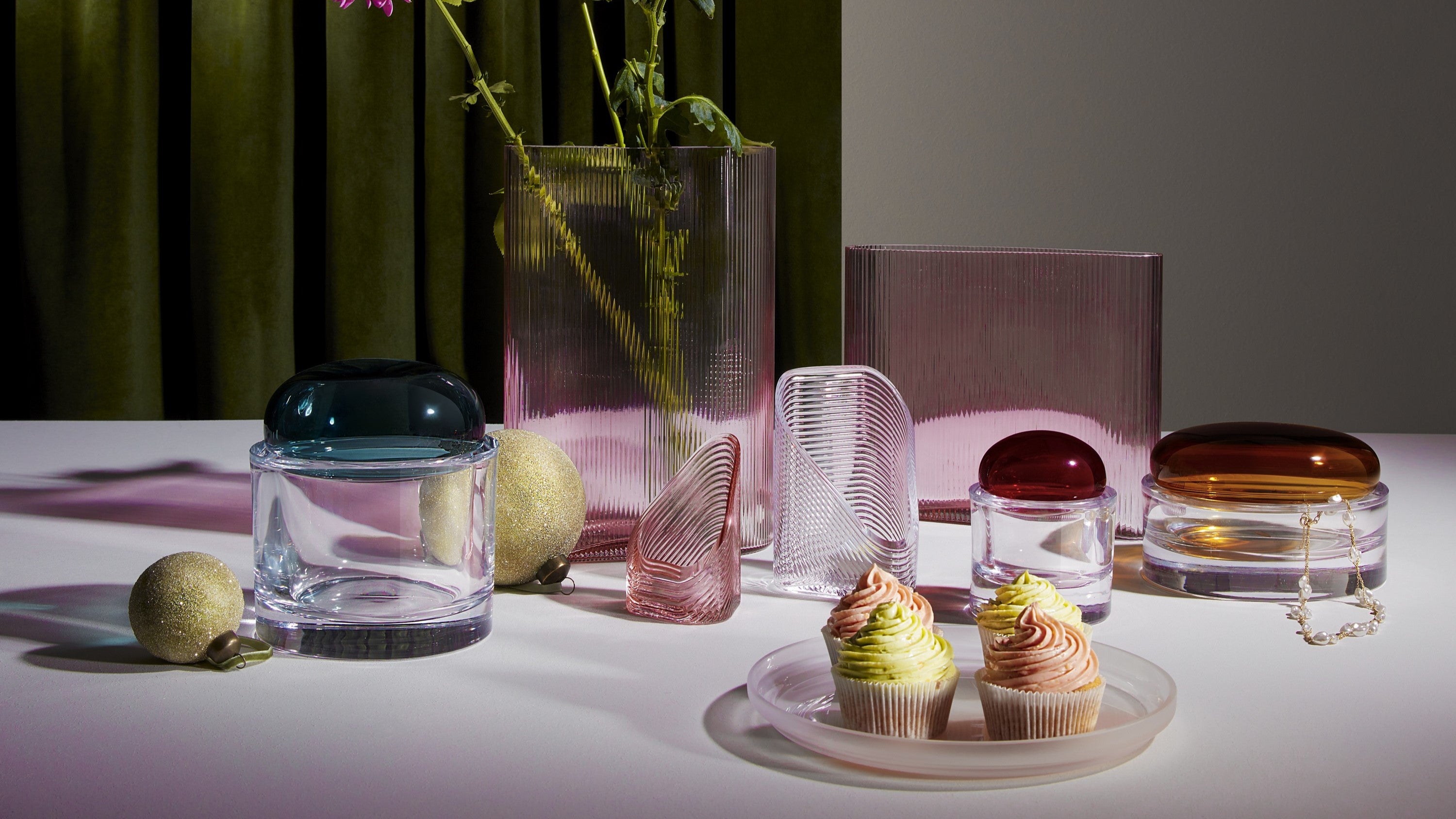 Lifestyle image with NUDE Lady water carafe and water glasses presented on side table and the NUDE Layers vase in amber with the Layers tall vase in acid grey presented as a group