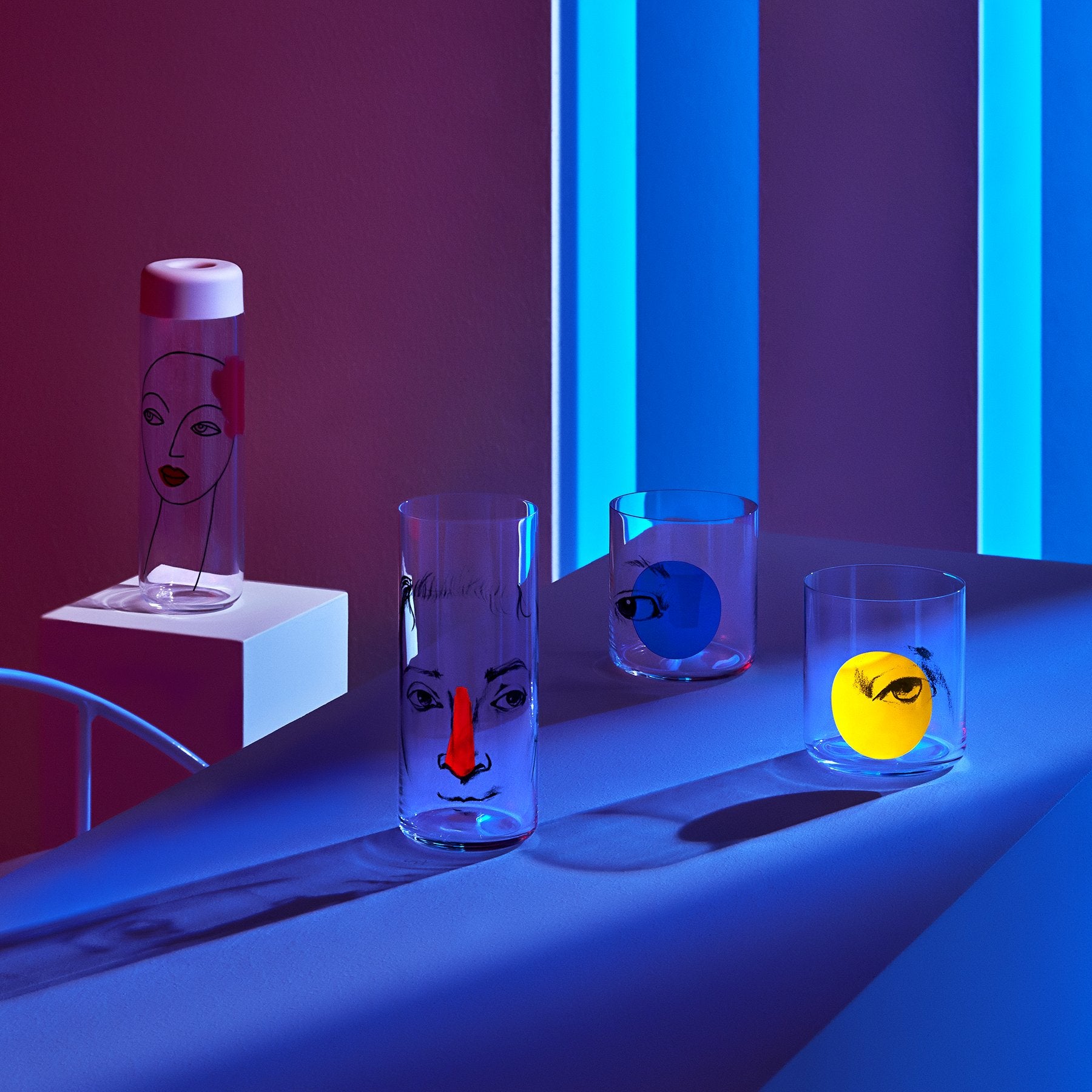 Lifestyle image of NUDE Rock &amp; Pop glass collection with jug, highball glass and whisky glass in dark neon environment