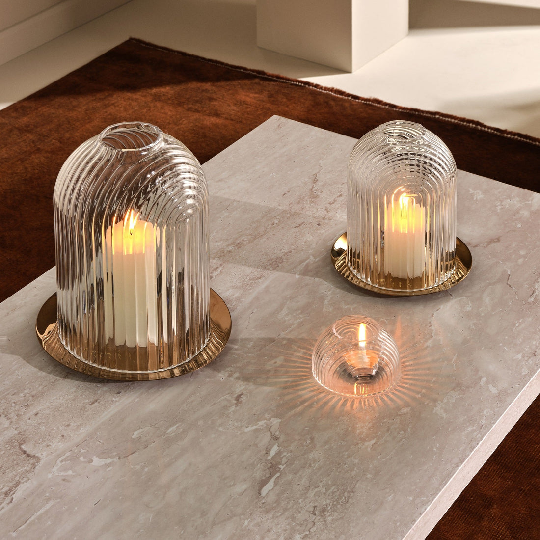 Lead-free crystal candle holder Ilo, a dome shaped candle holder with rippled glass effect, with candle presented on a table with the small version of candle holder and a votive version of similar design